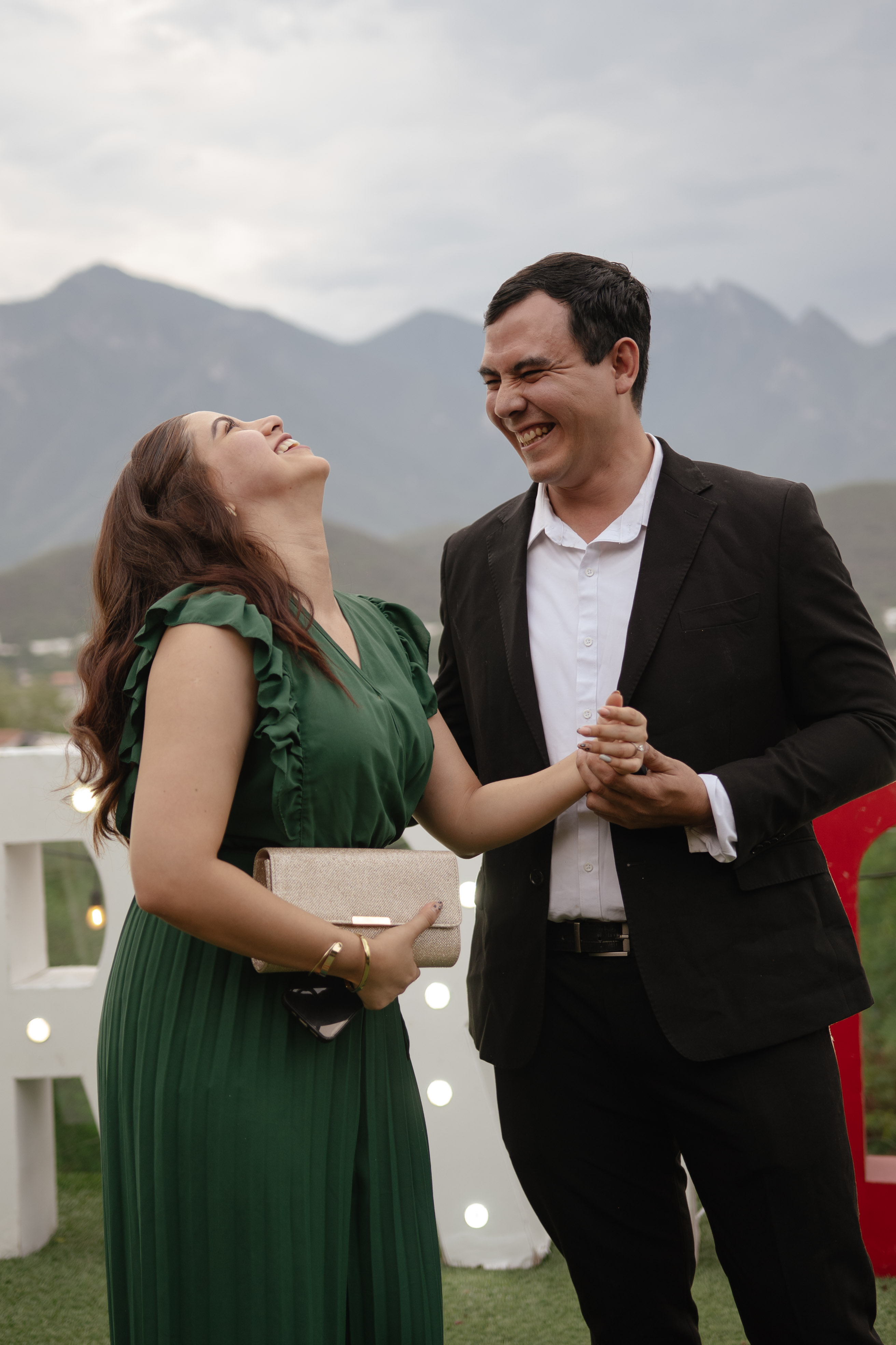 Pareja celebrando con carcajadas frente al lago y la sierra de Monterrey
